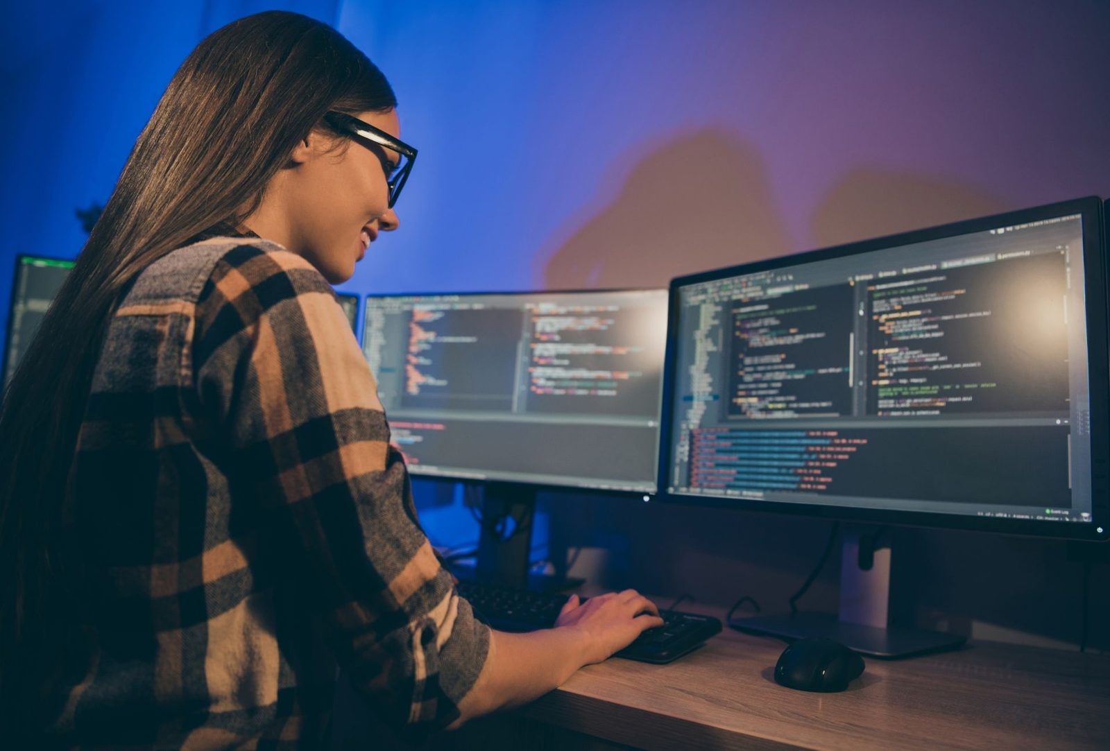 An engineer writing code across two monitors